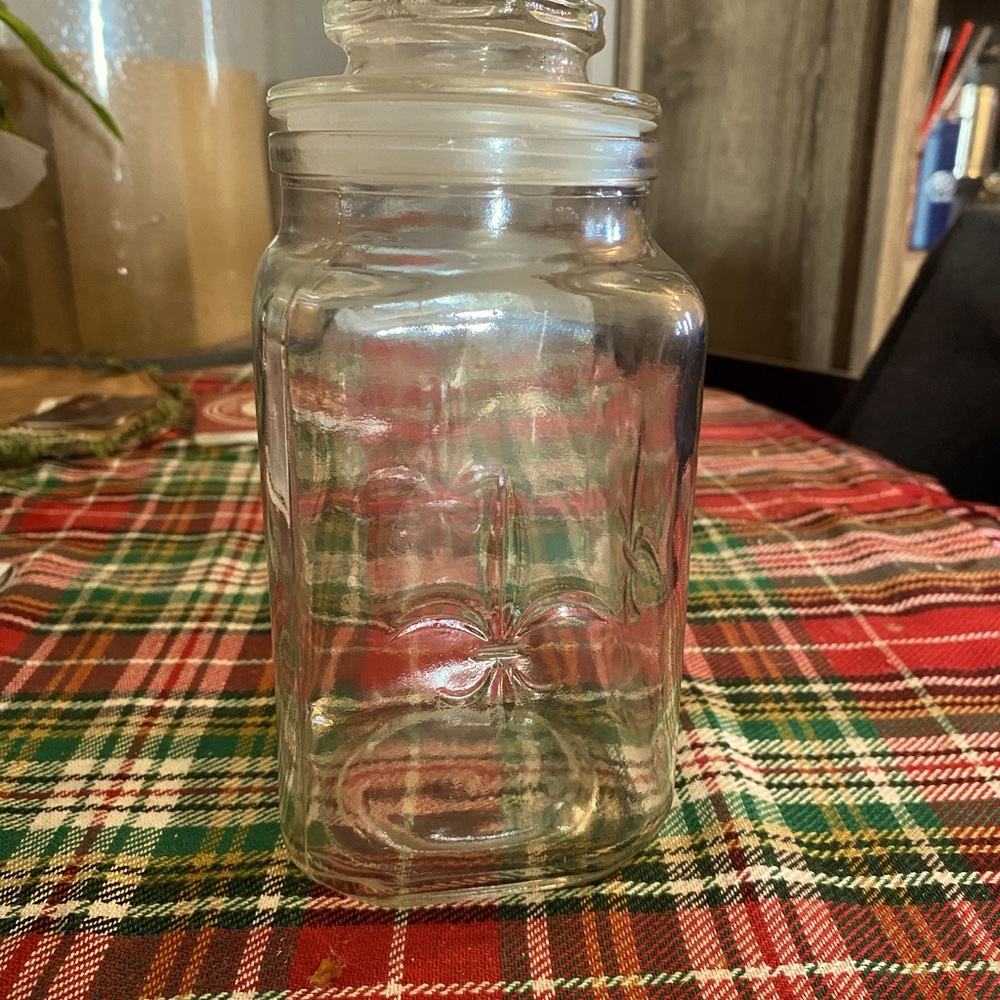 Clear glass jar and top with Fleur De Leis design